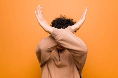 Genç karışık afrikalı-amerikalı kadın kahverengi bir arka plan karşı iki kol çapraz tutarak, inkar kavramı.