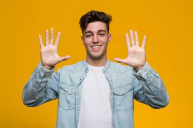 Genç yakışıklı öğrenci elleri ile on numara gösteren bir kot gömlek giyiyor.