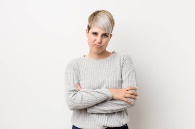 Beyaz arka planda izole edilmiş genç kıvrımlı beyaz beyaz kadın hoşnutsuzluk içinde yüzünü kaşlarını çattı, kollarını katlanmış tutar.