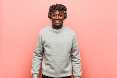 Genç rasta siyah adam kulaklık mutlu, gülümseyen ve neşeli ile müzik dinliyor.