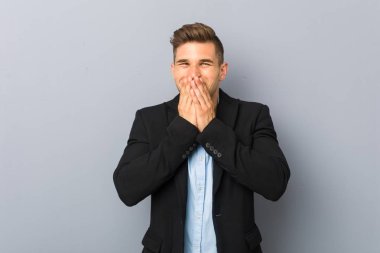 Genç yakışıklı beyaz adam bir şey hakkında gülüyor, elleriyle ağız kapsayan.