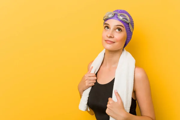 Young caucasian swimmer woman against a yellow background