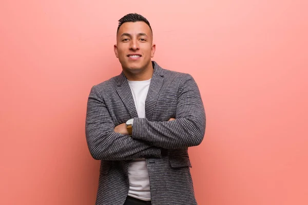 Young elegant latin man crossing arms, smiling and relaxed