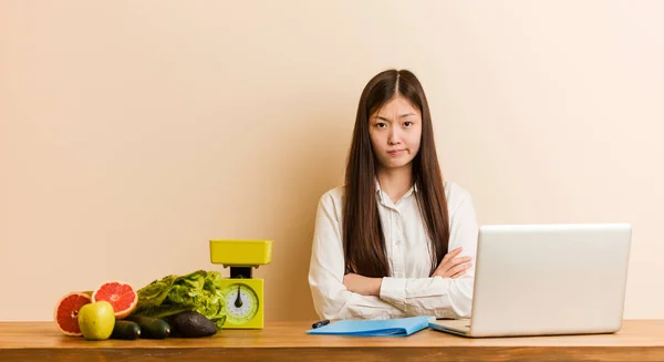 Young nutritionist chinese woman working with her laptop unhappy looking in camera with sarcastic expression.