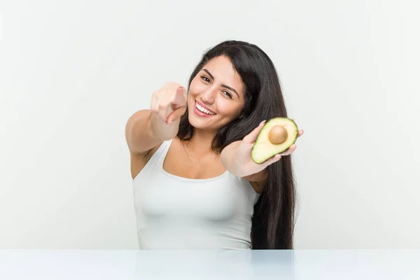 Joven Mujer Hispana Sosteniendo Una Alegre Sonrisa Aguacate Apuntando Frente —  Fotos de Stock