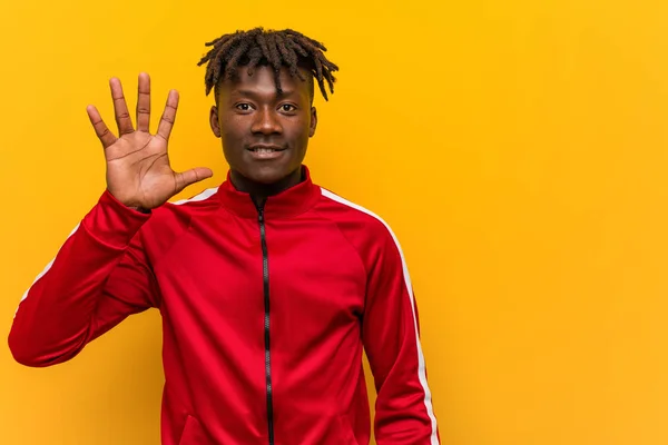 Young fitness black man smiling cheerful showing number five with fingers.