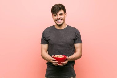 Bir tahıl kase mutlu, gülümseyen ve neşeli tutan genç İspanyol adam.