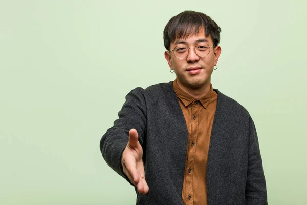 Young chinese man wearing a cool clothes style against a green b — Stock Photo, Image