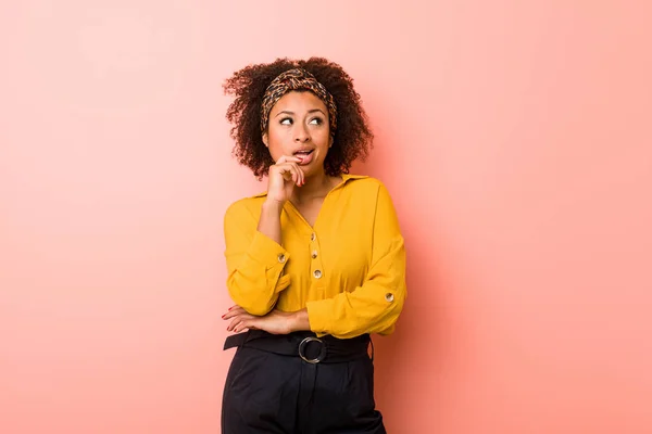 Jovem Afro Americana Contra Fundo Rosa Relaxado Pensando Algo Olhando — Fotografia de Stock