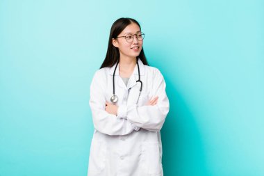 Genç Çinli doktor kadın çapraz kolları ile kendinden emin gülümseyen.