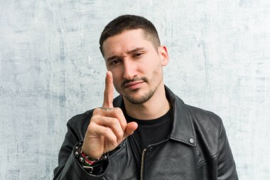 Genç rockçı adam parmak ile bir numara gösteren.