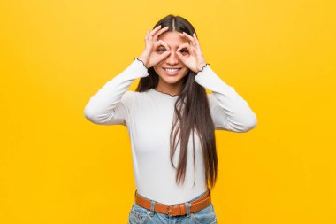 Gözleri üzerinde tamam işareti gösteren sarı bir arka plan karşı Genç güzel arap kadın