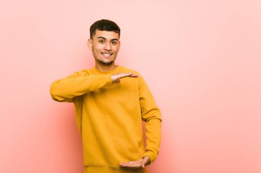 Genç İspanyol adam iki eliyle bir şey tutarak, ürün sunumu.