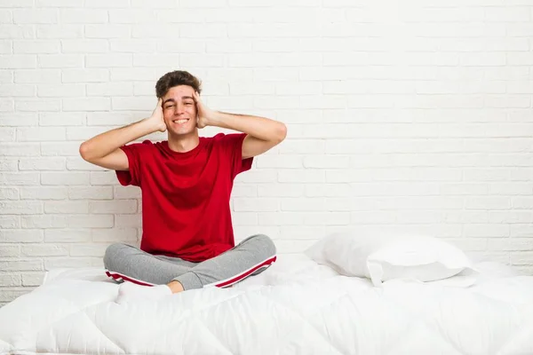 Yatakta Genç Genç Öğrenci Adam Sevinçle Baş Elleri Tutarak Gülüyor — Stok fotoğraf