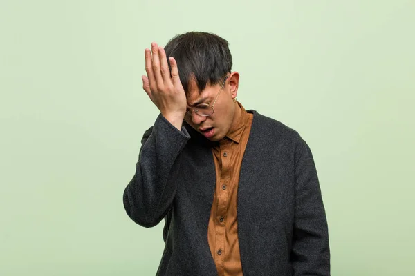 Homem chinês jovem contra uma parede verde — Fotografia de Stock