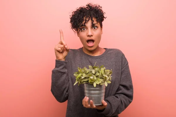 Jovem Afro Americana Segurando Uma Planta Relaxada Pensando Algo Olhando — Fotografia de Stock