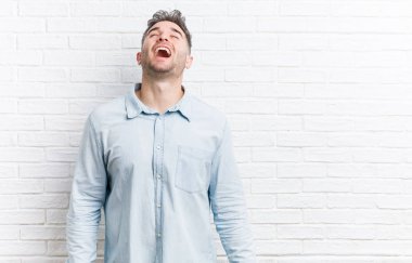 Duvara yaslanmış yakışıklı bir delikanlı gevşemiş ve mutlu bir gülüş, dişlerini gösteren bir boyun..