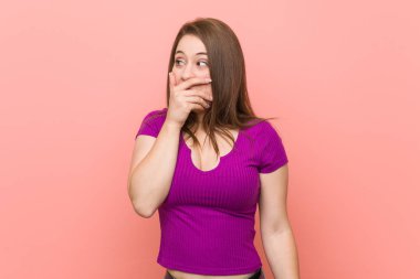 Pembe bir duvara karşı genç İspanyol kadın düşünceli el ile ağız kapsayan bir kopyasını alan arıyor.