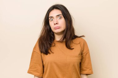 Bej arka plan karşı Genç esmer kadın omuzsilke ve açık gözleri karışık.