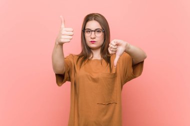 Gözlük takan genç öğrenci kadın başparmak yukarı ve başparmak aşağı gösteren, zor kavramı seçin