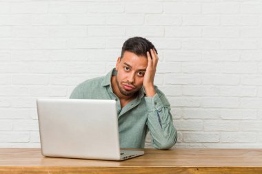 Genç filipinli adam onun laptop yorgun ve çok uykulu baş el tutmak ile çalışan oturuyor.