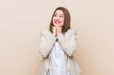 Genç iş kadını çenealtında ellerini tutar, bir yana mutlu görünüyor.