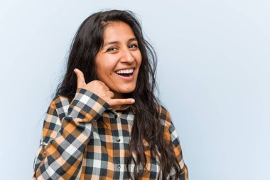 Genç serin hintli kadın parmakları ile bir cep telefonu arama jesti gösteren.