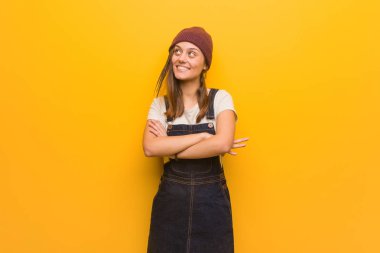 Genç hipster kadın kendinden emin gülümseyen ve kollarını geçiş, yukarı bakıyor