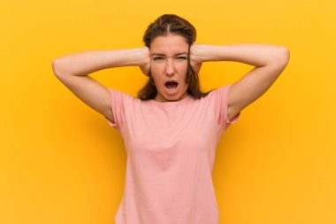Genç Avrupalı kadın çok yüksek ses duymamaya çalışırken elleri ile kulaklarını kaplayan sarı arka plan üzerinde izole.