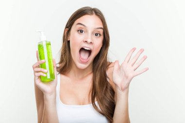 Bir zafer ya da başarı kutlayan bir aloe vera şişesi tutan genç beyaz kadın