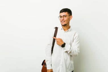 Genç İspanyol rahat iş adamı gülümseyerek ve bir kenara işaret, boş alanda bir şey gösteren.