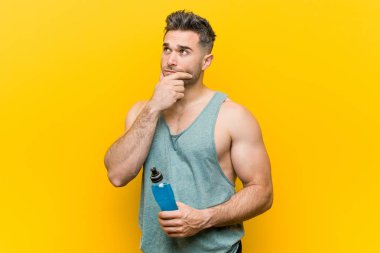 Şüpheli ve şüpheci ifade ile yana bakan bir enerji içeceği tutan Kafkas adam.