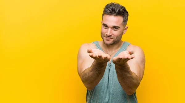 Jonge Fitnessman Tegen Een Gele Achtergrond Met Iets Met Handpalmen — Stockfoto