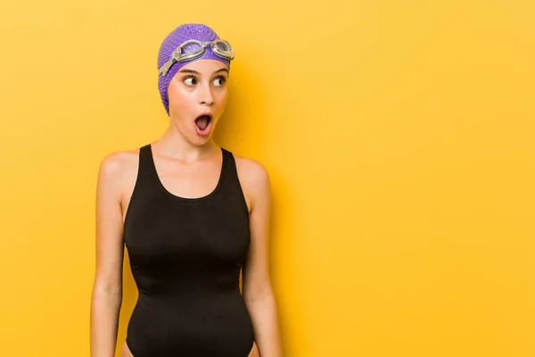 Young swimmer caucasian woman being shocked because of something she has seen.