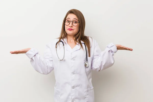 Jonge Dokter Vrouw Tegen Een Witte Muur Twijfelen Afschudden Schouders — Stockfoto