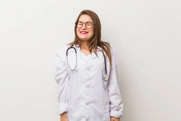 Jonge Dokter Vrouw Tegen Een Witte Muur Lacht Sluit Ogen — Stockfoto