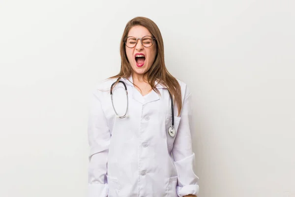 Młody Lekarz Kobieta Przeciwko Białej Ścianie Krzyczeć Bardzo Zły Agresywny — Zdjęcie stockowe