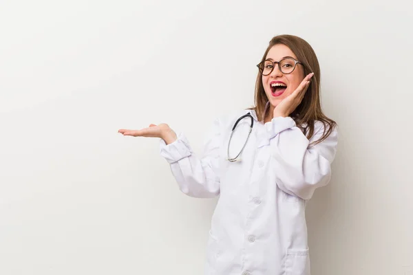 Jonge Dokter Vrouw Tegen Een Witte Muur Houdt Kopie Ruimte — Stockfoto