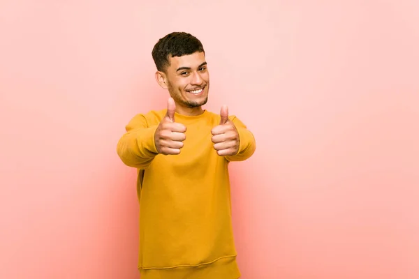 Young hispanic man with thumbs ups, cheers about something, support and respect concept.