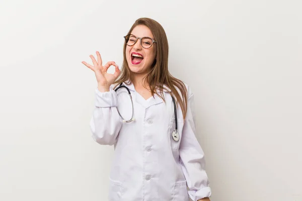 Jonge Dokter Vrouw Tegen Een Witte Muur Knikt Een Oog — Stockfoto