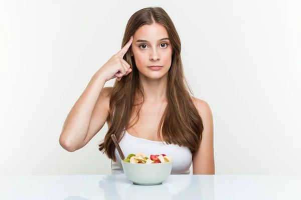 Giovane Donna Caucasica Mangiare Frutta Ciotola Puntando Suo Tempio Con — Foto Stock