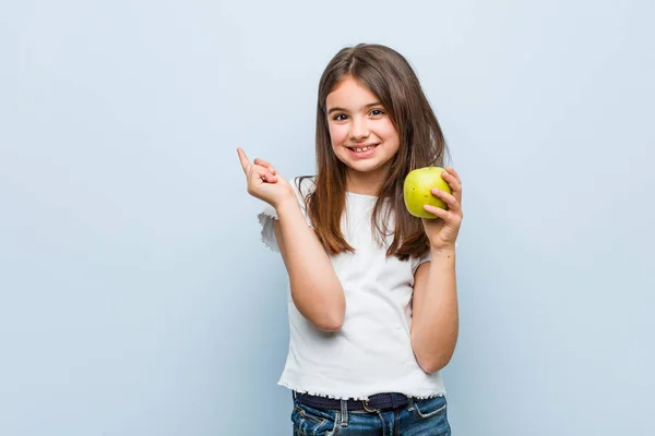 Pequeña Chica Caucásica Sosteniendo Una Manzana Verde Sonriendo Alegremente Señalando — Foto de Stock