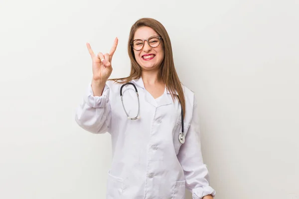 Jonge Dokter Vrouw Tegen Een Witte Muur Tonen Een Hoorns — Stockfoto