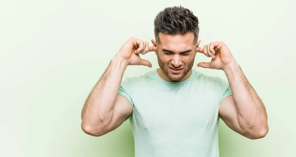 Joven Hombre Guapo Sobre Fondo Verde Cubriendo Las Orejas Con — Foto de Stock