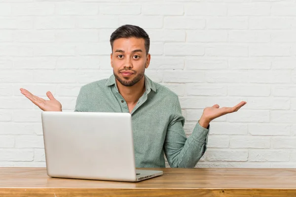 Young Filipino Man Sitting Working His Laptop Confused Doubtful Shrugging — Stock Photo, Image