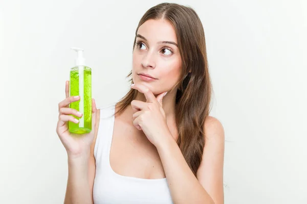 Joven Mujer Caucásica Sosteniendo Una Botella Aloe Vera Mirando Lado —  Fotos de Stock