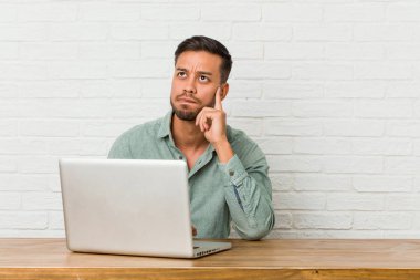 Genç filipinli adam onun laptop ile çalışan oturan karışık, şüpheli ve emin hissediyor.