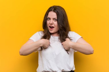 Genç kıvrımlı artı boyutu kadın kendini işaret şaşırttı, geniş gülümseyerek.