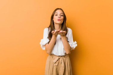 Beyaz kadın dudaklarını katlıyor ve hava öpücüğü vermek için avuçlarını tutuyor..