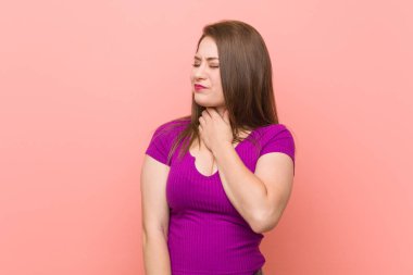 Pembe bir duvara karşı Genç İspanyol kadın bir virüs veya enfeksiyon nedeniyle boğaz ağrısı uğrar.